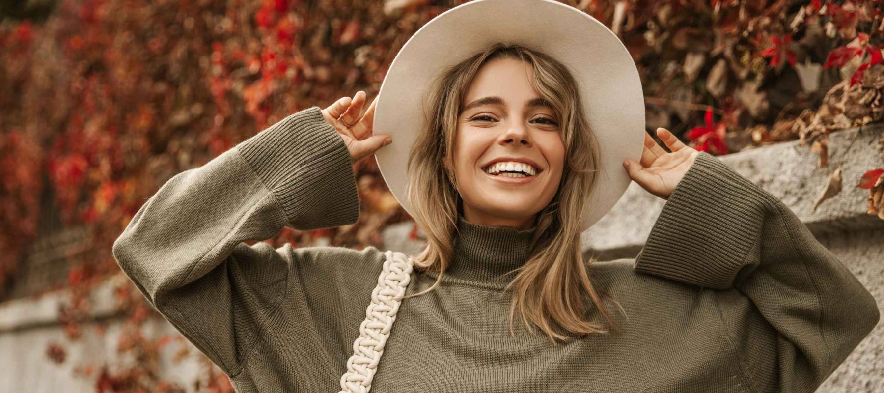 Attractive stylish woman holding hat on head