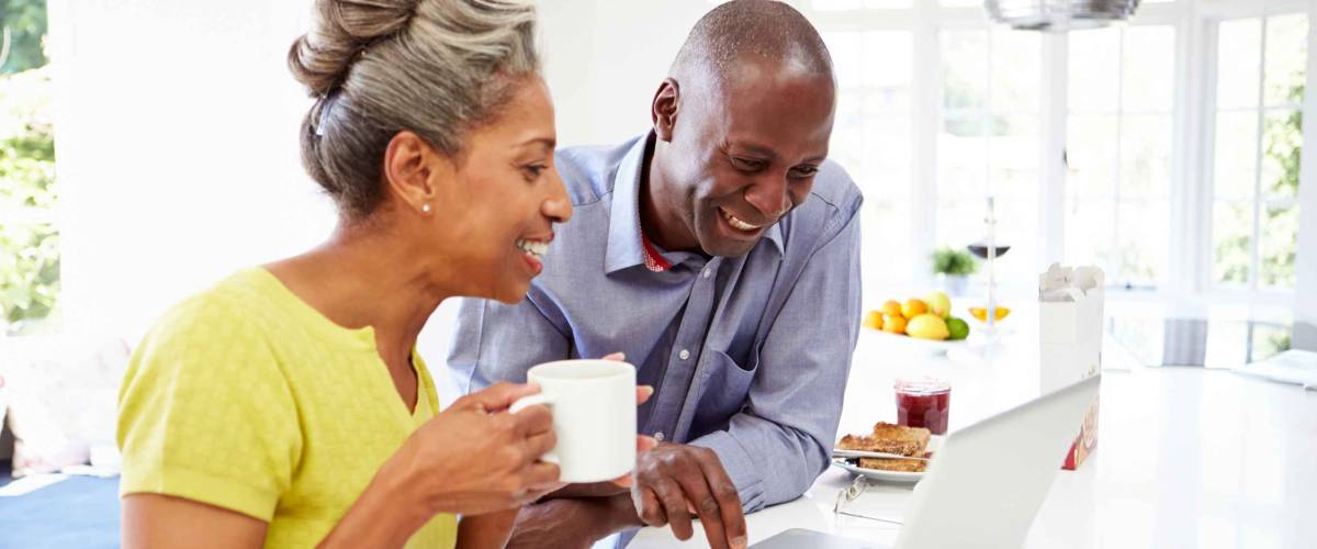 Mature African American Couple Using Laptop At Breakfast