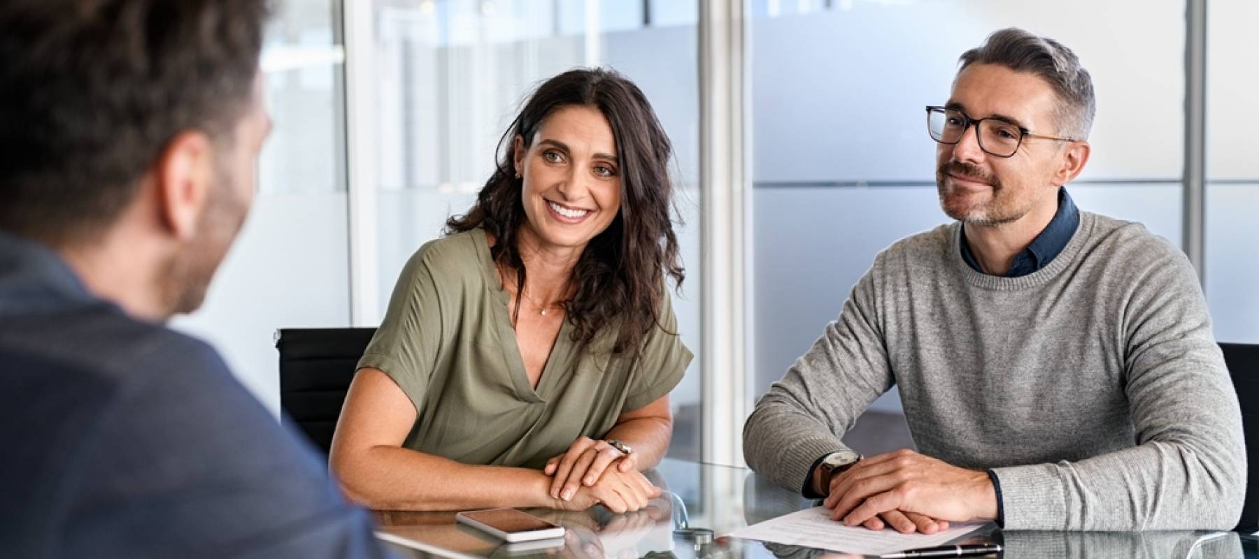 Happy, smiling couple meet in corporate office with financial planner.