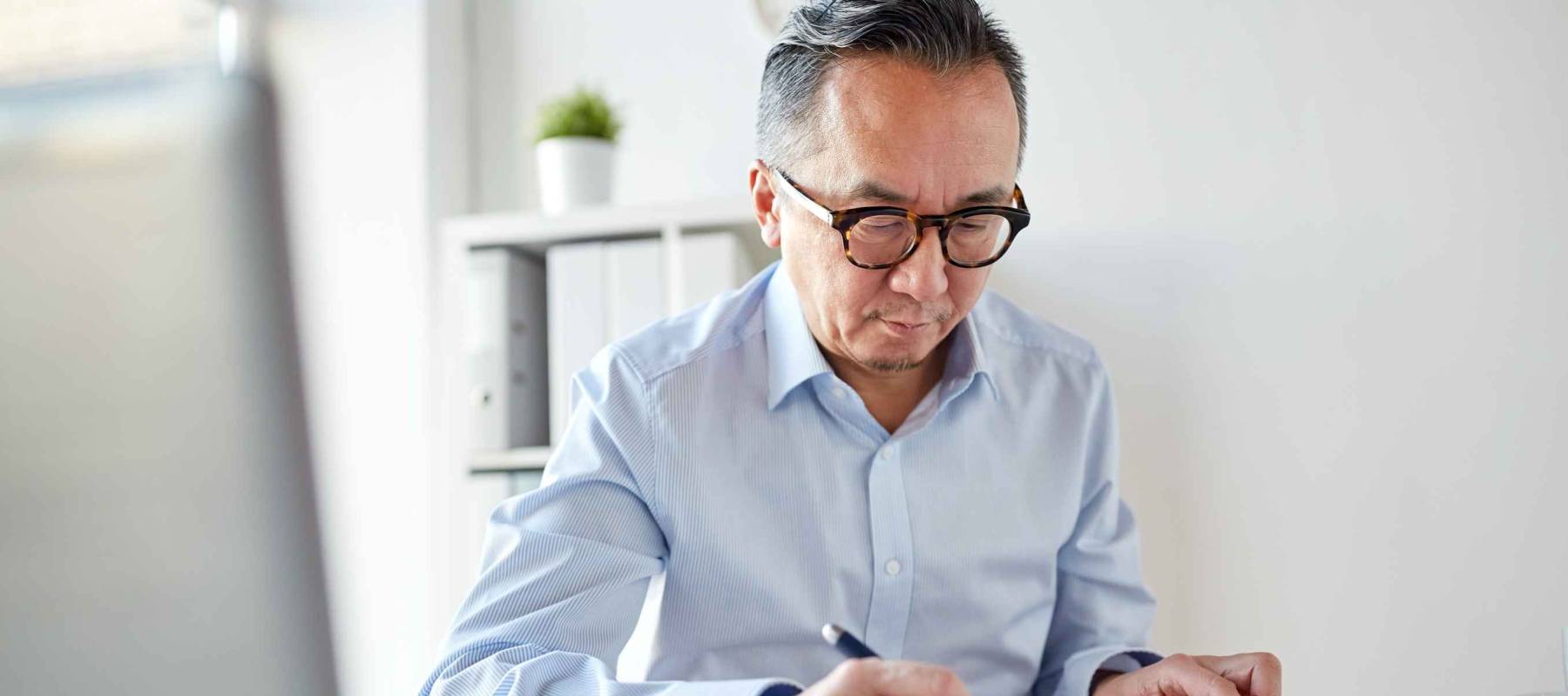 business, people, paperwork and technology concept - businessman with calculator and paper working in office