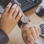 businesswoman boss checking the time on watch waiting for partners coming late sitting at her desk office