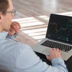Close up shot of trade investor sitting with laptop on knees,