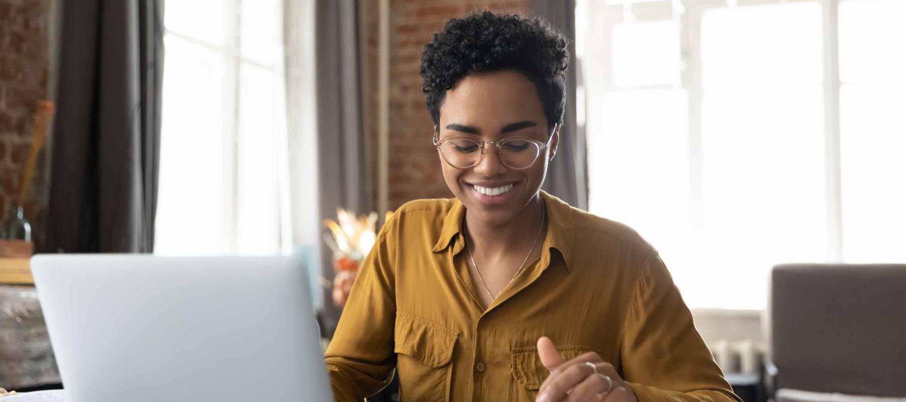Happy young Afro American entrepreneur woman in glasses counting profit, on calculator at laptop computer, analyzing benefits, enjoying financial success, job high result, smiling