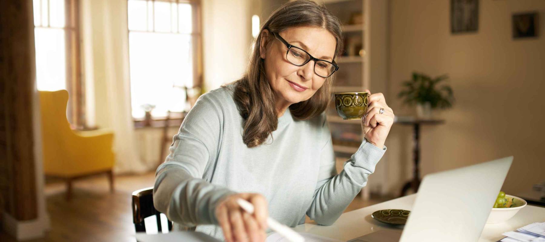 Serious confident middle aged female journalist on laptop at home