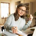 Serious confident middle aged female journalist on laptop at home