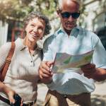 Portrait of senior tourist couple in town using a map. Mature man and woman using map while sightseeing.