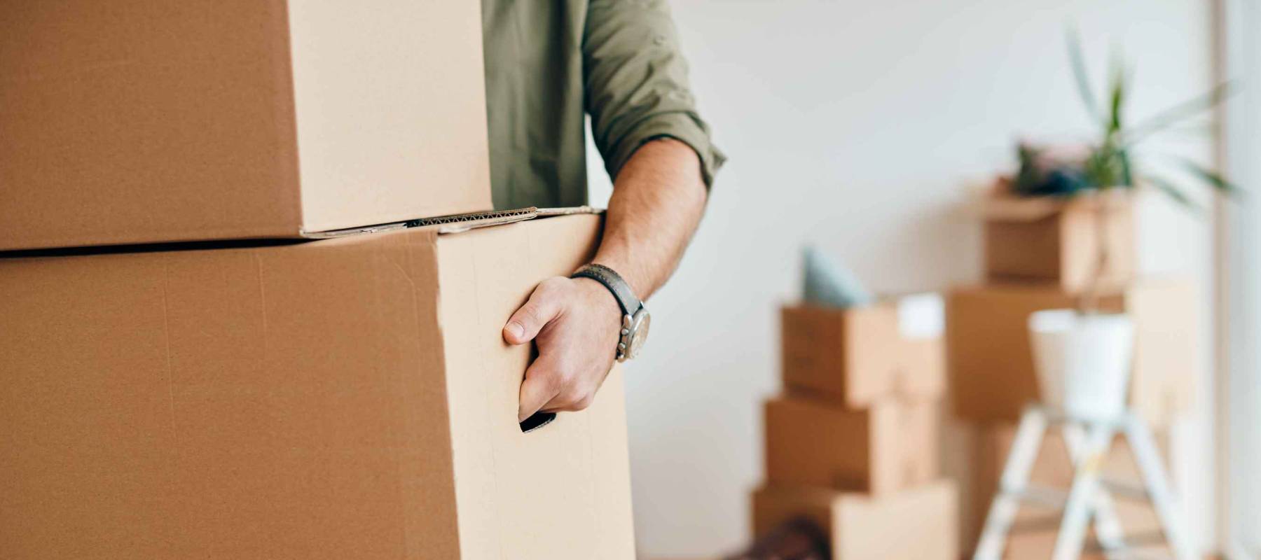 Close-up of a man with carton boxes moving into new home.