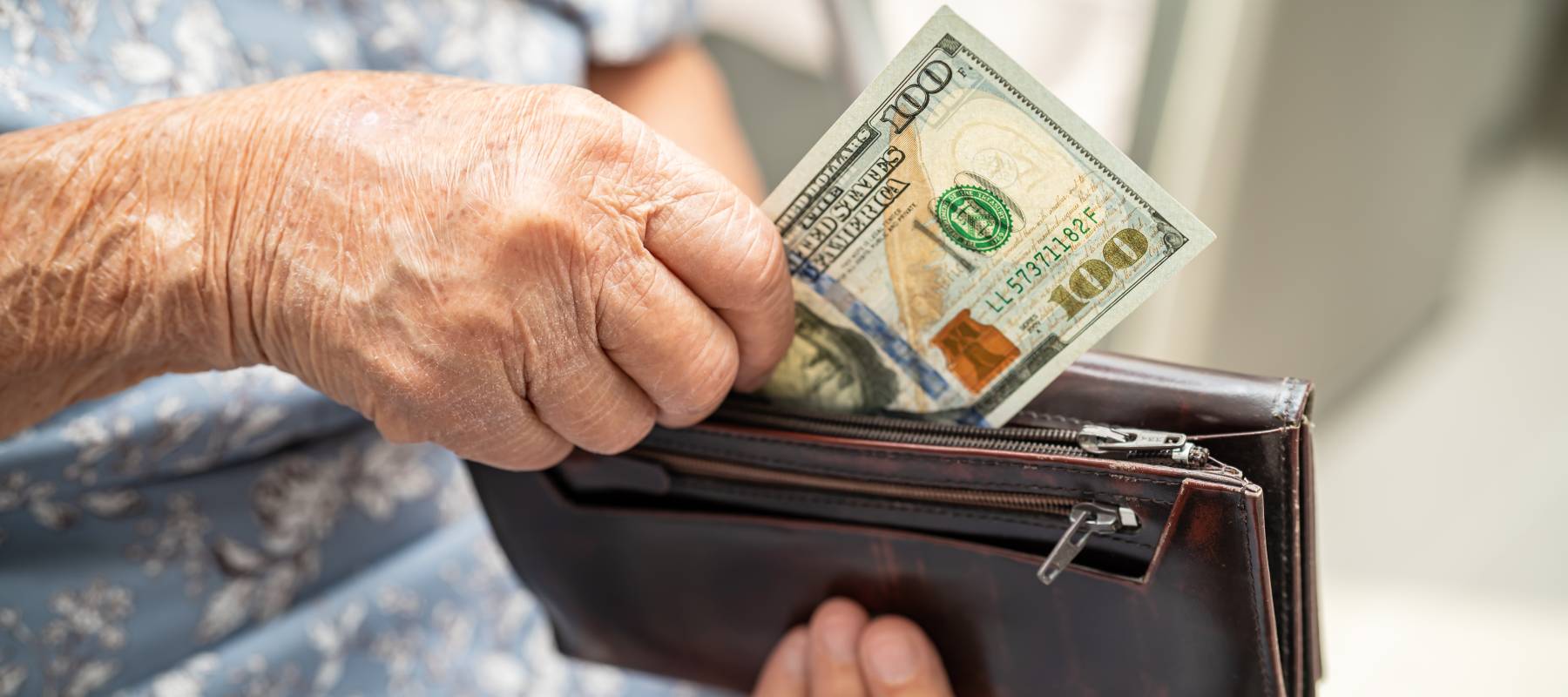 Senior person taking money out of their wallet.