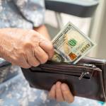 Senior person taking money out of their wallet.