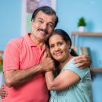 Older South Asian couple smiling while holding each other.
