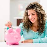 Young woman putting money into a piggy bank.