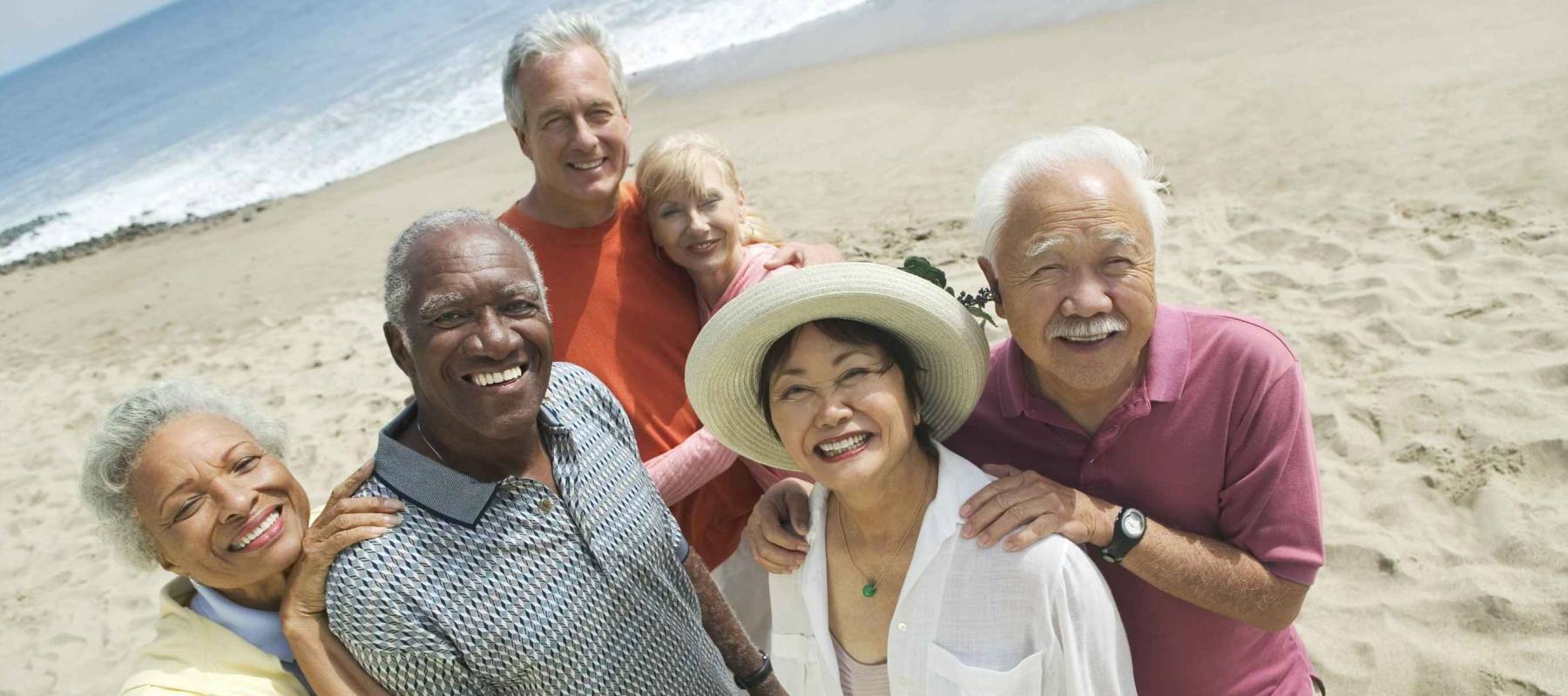 Group portrait of happy multiethnic couples smiling on the beach