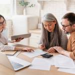 Consultant helping mature family couple at a desk with laptop ,calculator and paperwork