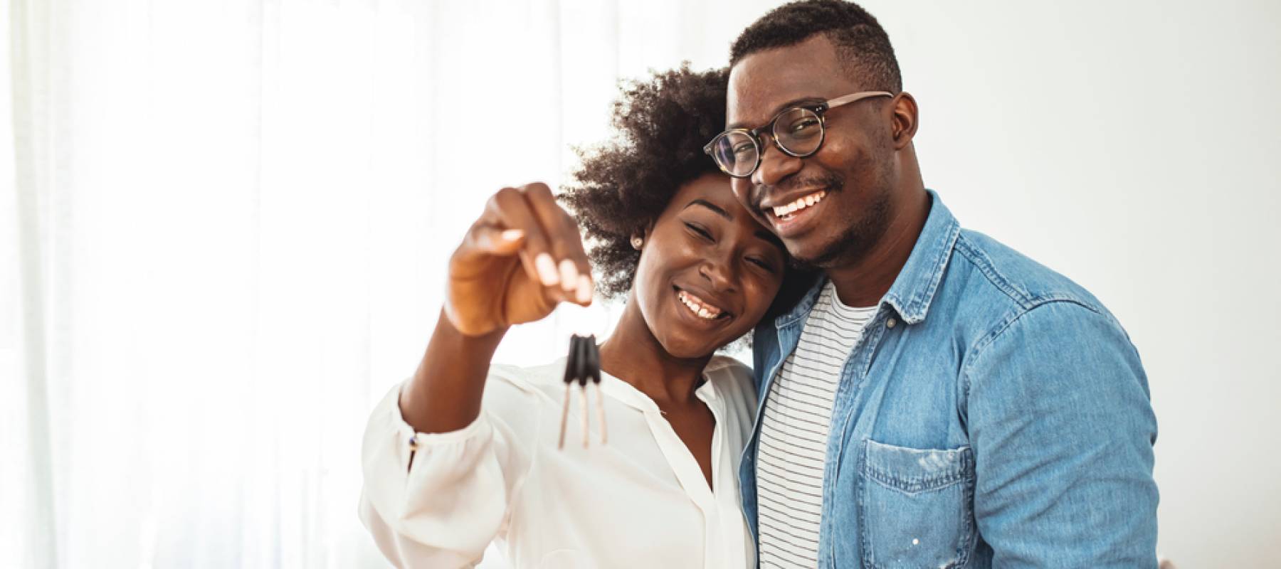 Happy young family couple holding key to new home on moving day concept
