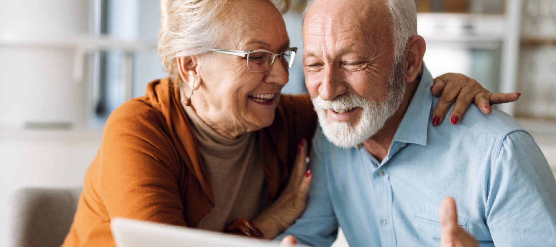Happy mature couple using laptop at home