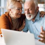 Happy mature couple using laptop at home