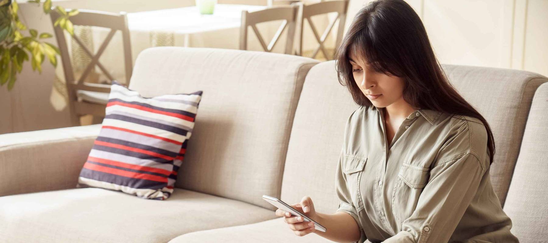 Young indian woman holding smart phone using mobile e-bank application