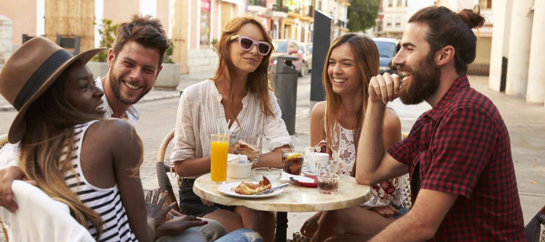 Friends on vacation laughing outside a cafe in Ibiza
