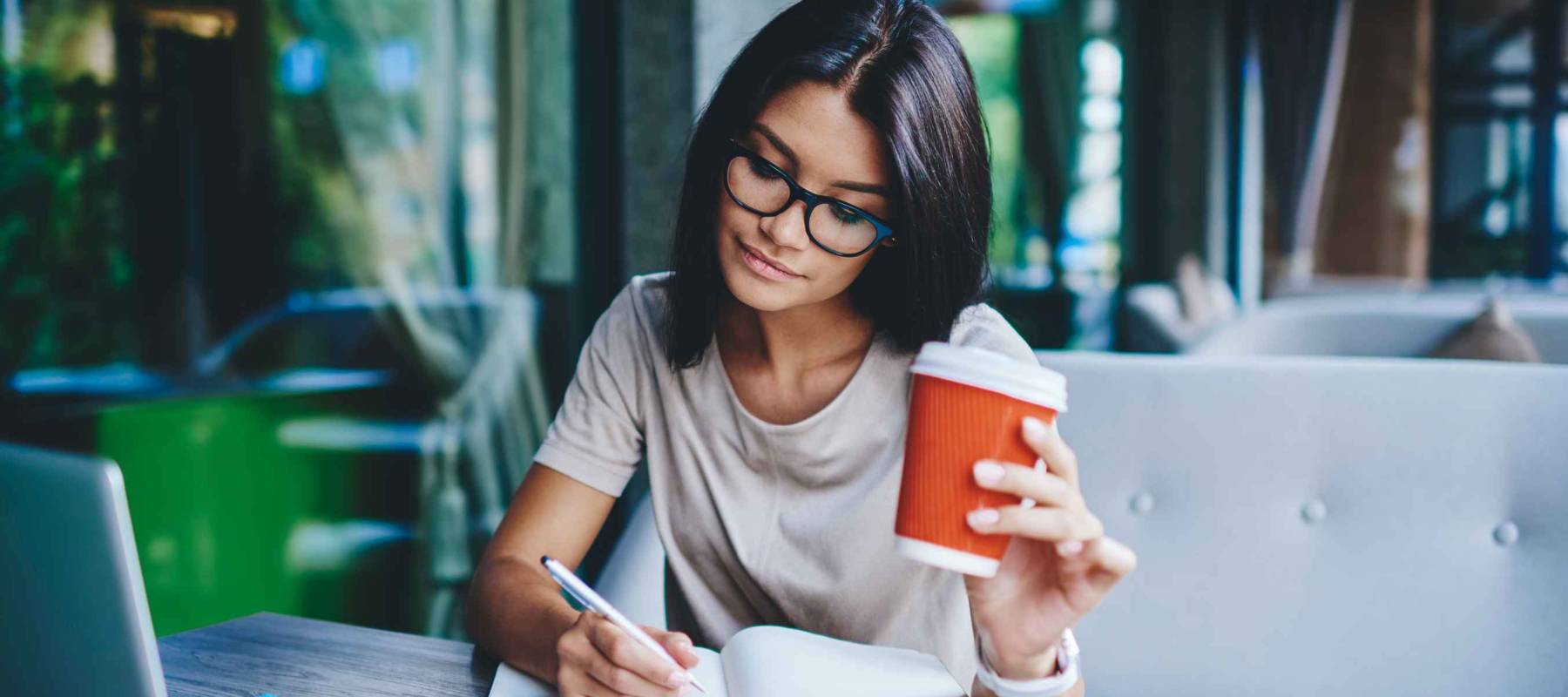 Concentrated female student writing in notebook while learning