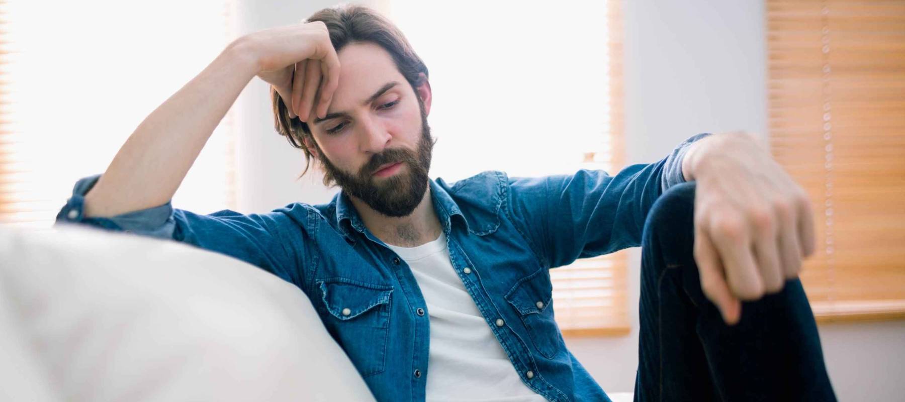 Unahppy man thinking on his sofa at home in the living room