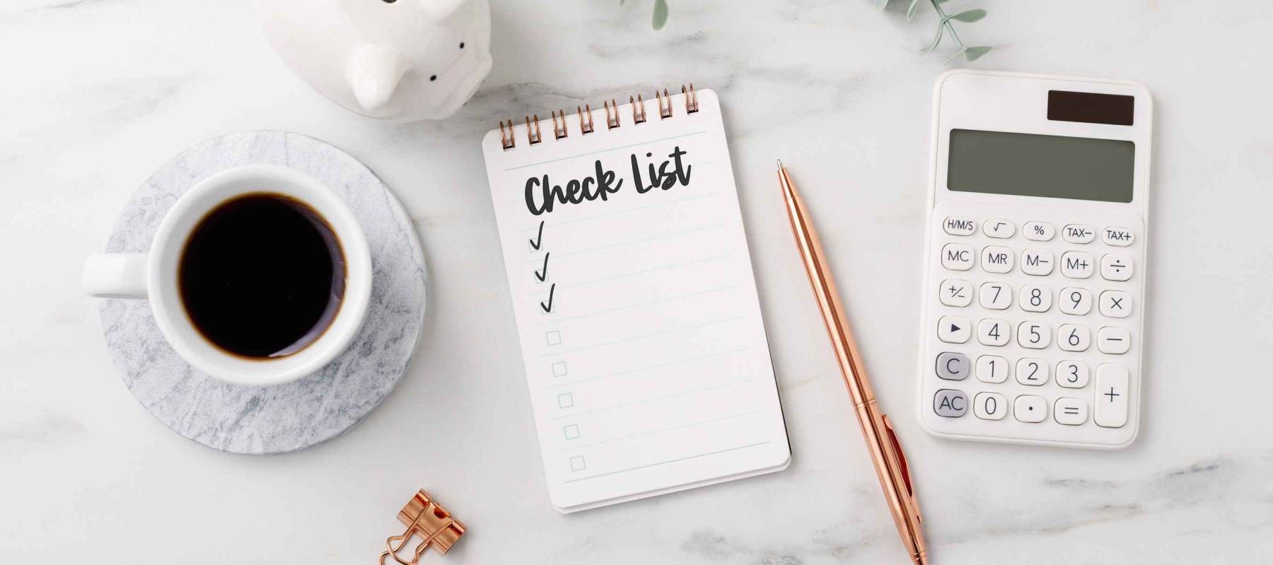 Financial planning checklist concept with calculator and piggy bank on marble table
