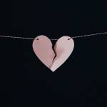 Paper heart torn in half held up by a piece of string