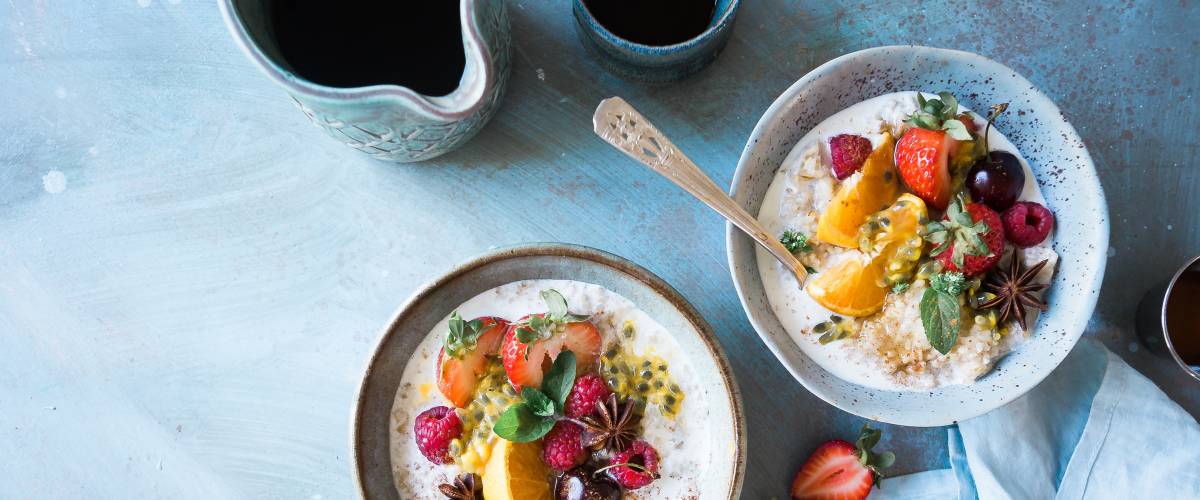 Bowl of oatmeal with fruit and coffee.