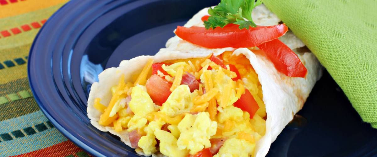 Delicious breakfast egg, tomato, cheese and pepper burrito.