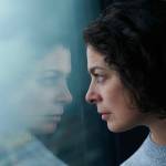 woman looking at reflection with a serious face