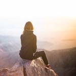 Woman sitting on mountain top making long term financial goals after paying off all her debt