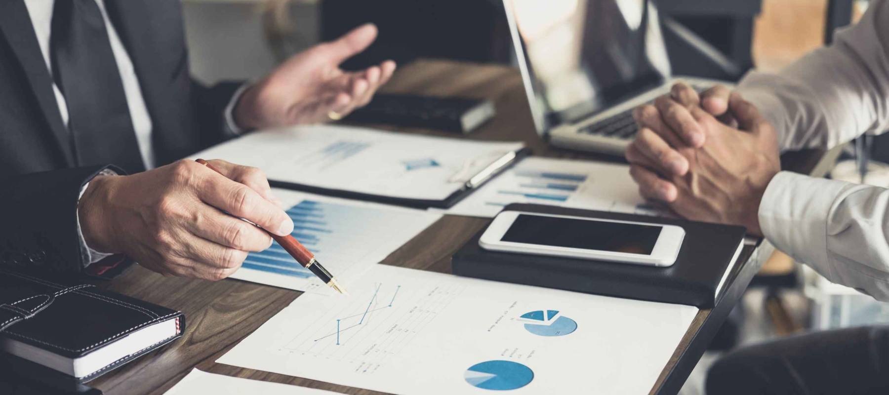 investor colleagues discussing new plan financial graph data on office table with laptop and digital tablet