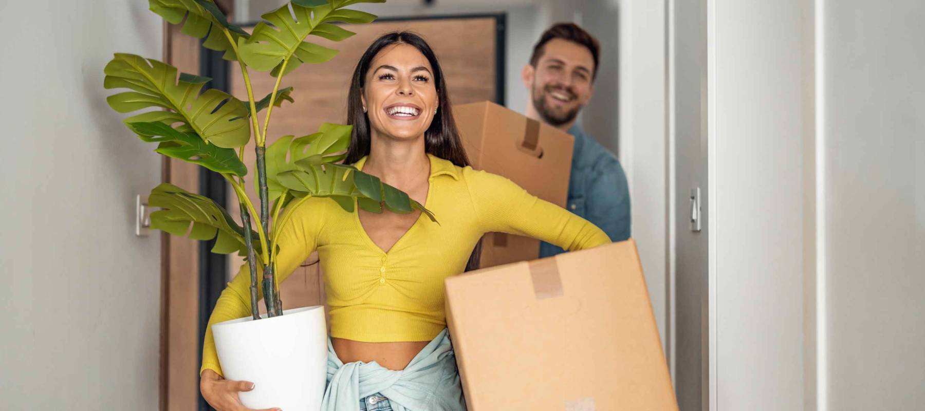 Young couple moving in new home.Couple is having fun with cardboard boxes in new house at moving day.