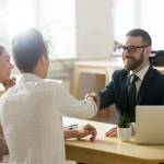 Smiling financial advisor handshaking young couple thanking shake hands making deal,