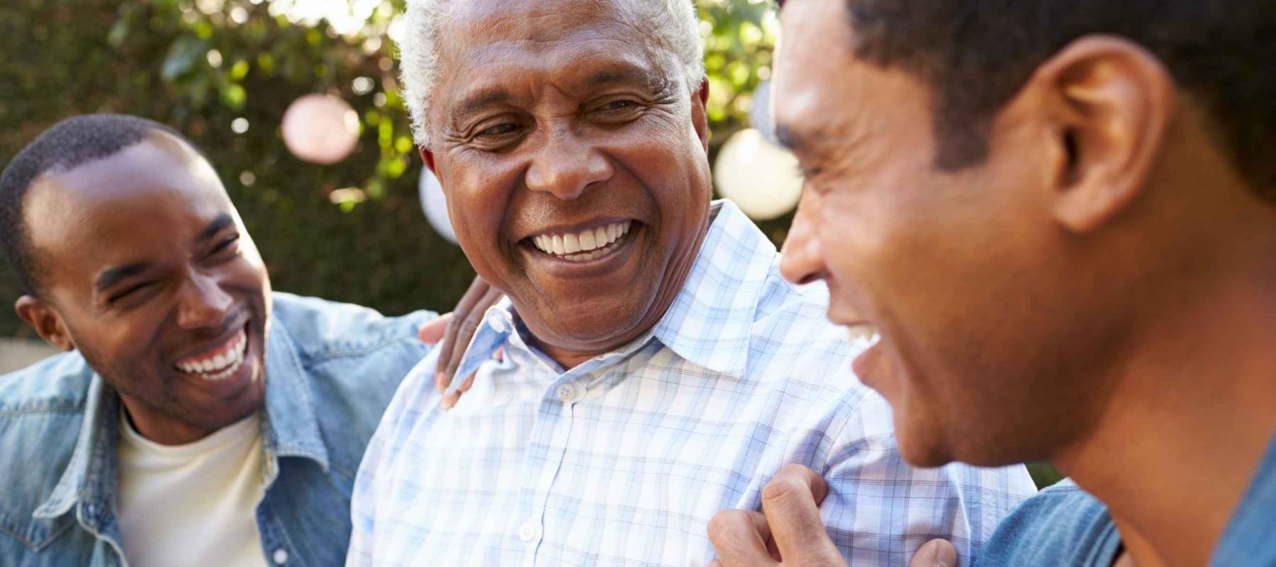 Senior man talking with his adult sons in garden, close up