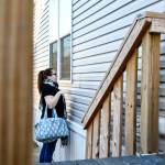 Woman looks into a window of a mobile home next to the front porch steps making a funny face to who is on the other side.