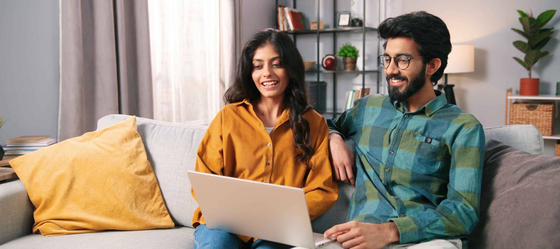 Portrait of young Indian happy cheerful family couple resting on sofa