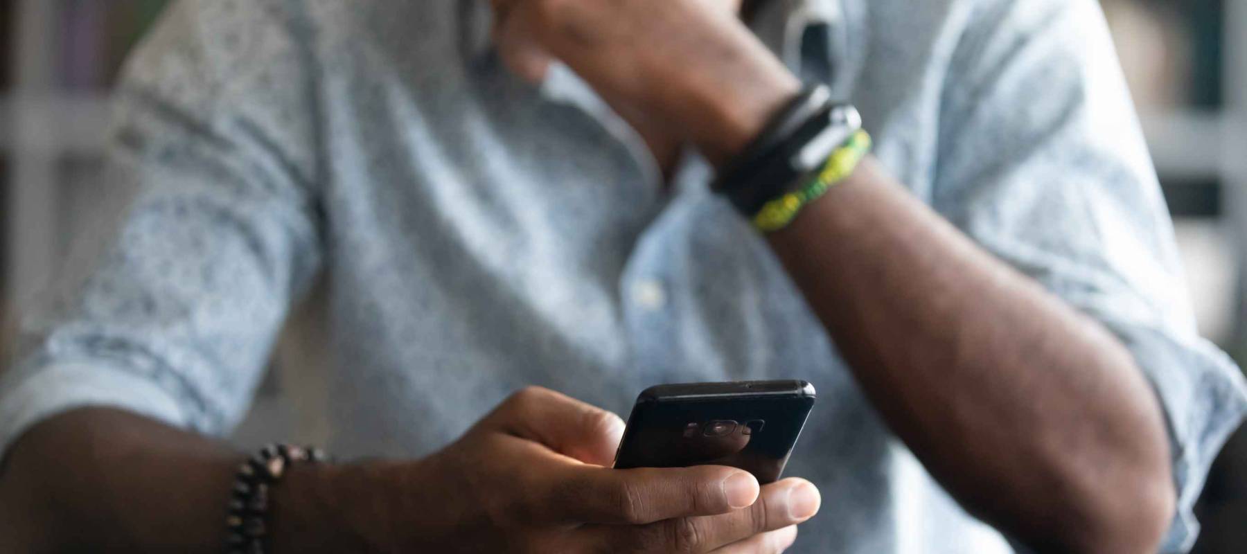 African guy holds cell phone close up view hands and device man