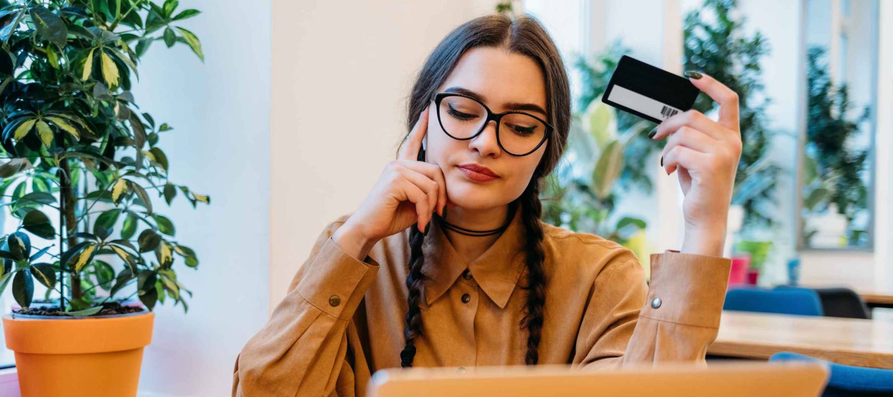 Portrait of young woman with laptop and credit card in cafe