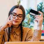 Portrait of young woman with laptop and credit card in cafe