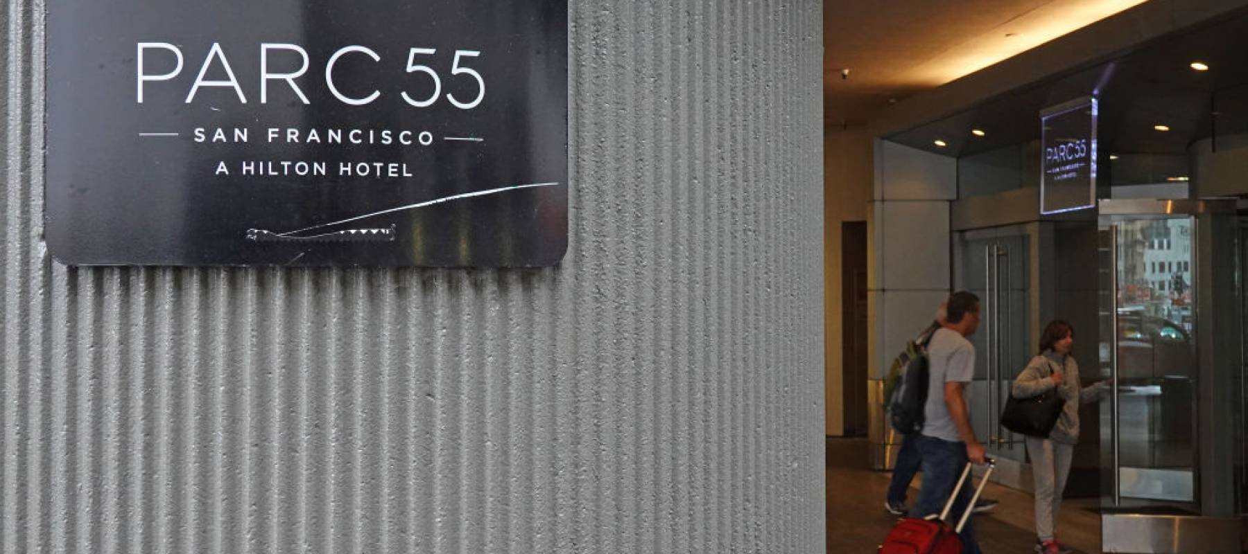 Close up of Parc 55 sign on hotel, while people in the background enter the lobby.