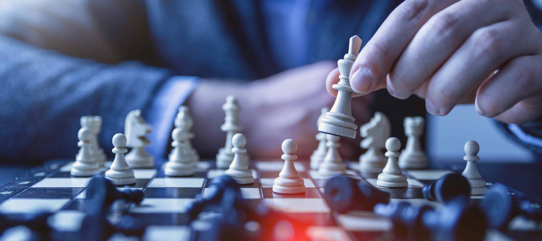 player playing chess holding up the white king with all the back pieces down on the board