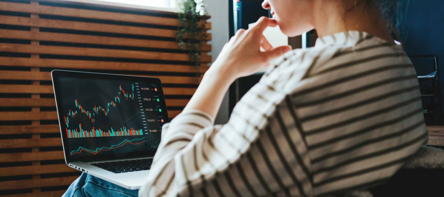 Woman investing in world stock market, using her laptop and online trading soft from home