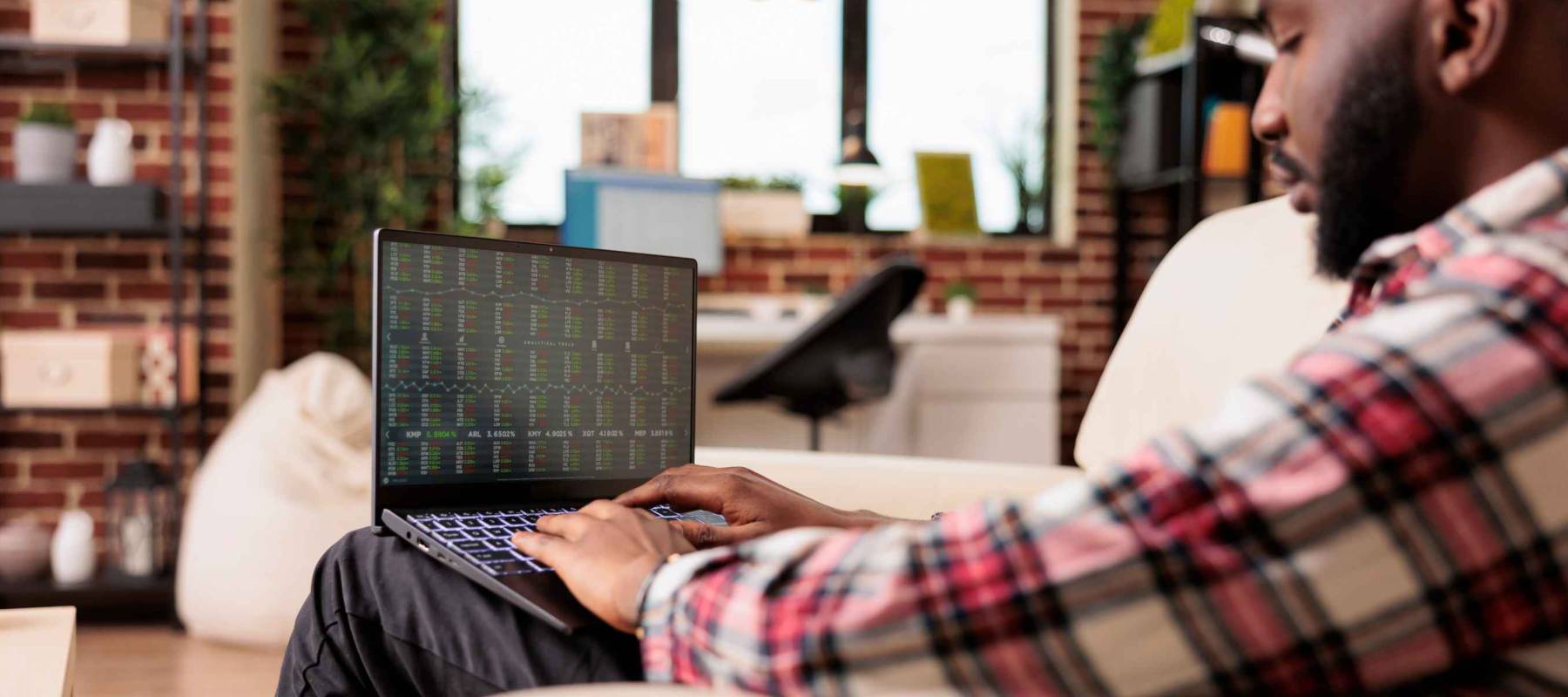 Financial analyst looking at stock market statistics, analyzing real time index profit exchange to do global money investment. Working remotely with capital trade business on laptop computer.