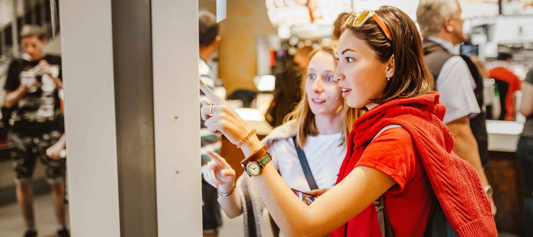 A woman orders food in the touch screen terminal with electronic menu in fast food restaurant