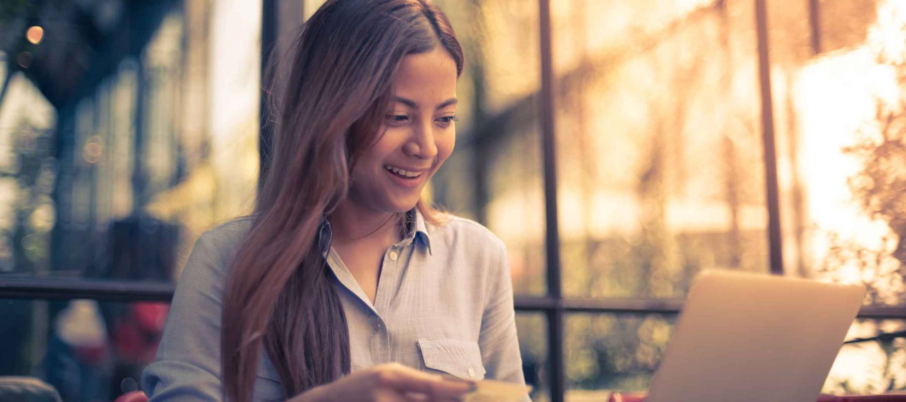 Asian woman shopping online with credit card and laptop in coffee shop