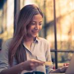 Asian woman shopping online with credit card and laptop in coffee shop
