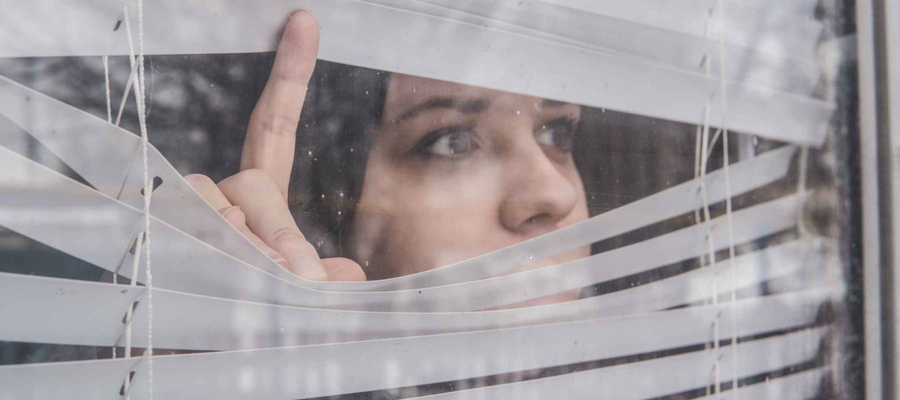 Woman Looking Through the Blinds. Girl looking out the window