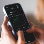 Stock market investor young woman holding a phone investment app index growth chart