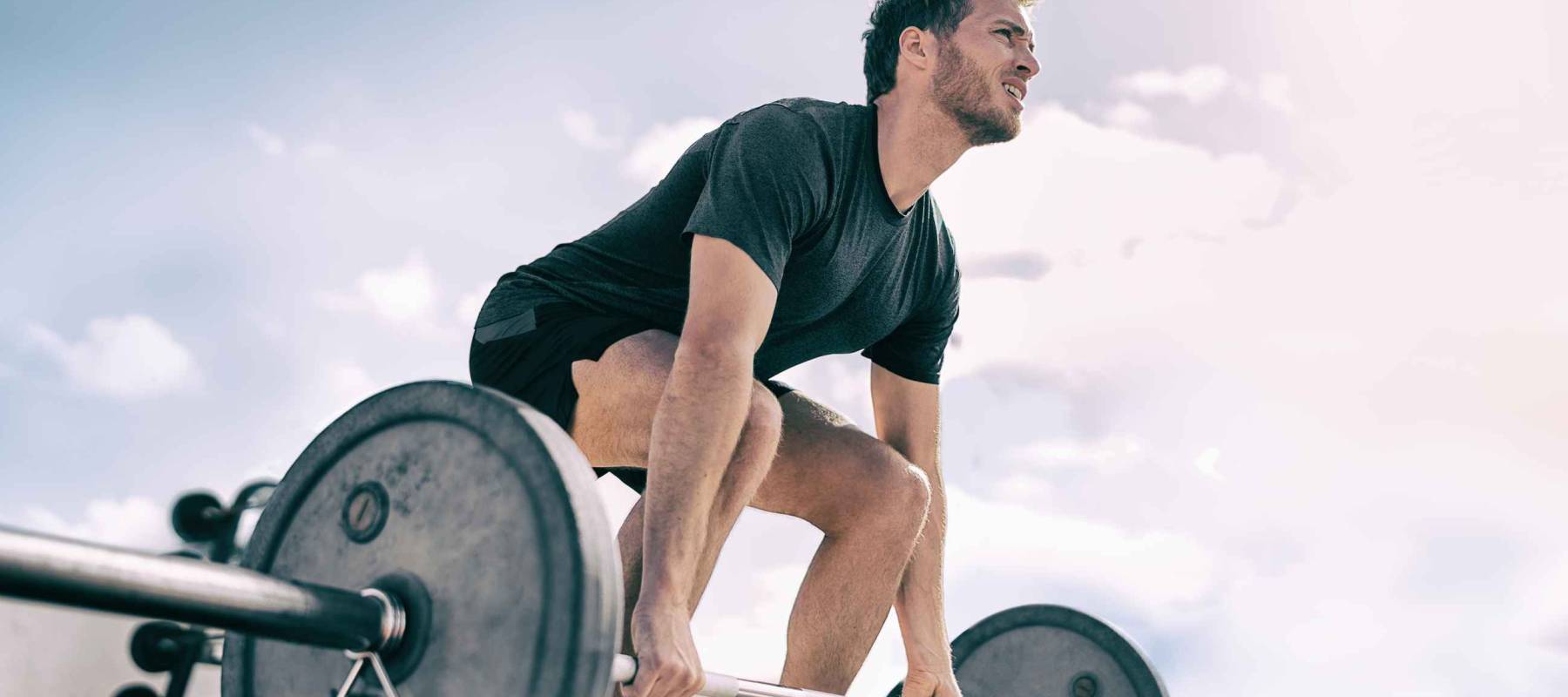 Gym fitness weightlifting deadlift man bodybuilding powerlifting at outdoor summer health club. Bodybuilder doing barbell weight lifting training workout with heavy bar.
