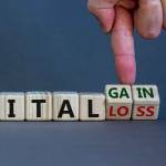 Capital loss or gain symbol. Male hand turns cubes and changes words 'capital loss' to 'capital gain'. Beautiful grey background. Business and capital loss or gain concept. Copy space.